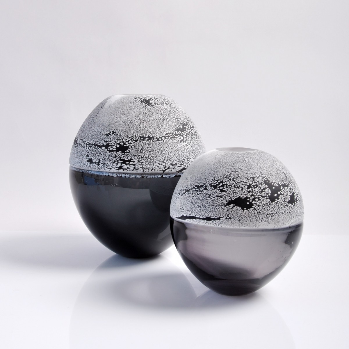 Two glass vases with grey bottom halves and black and white patterned top halves